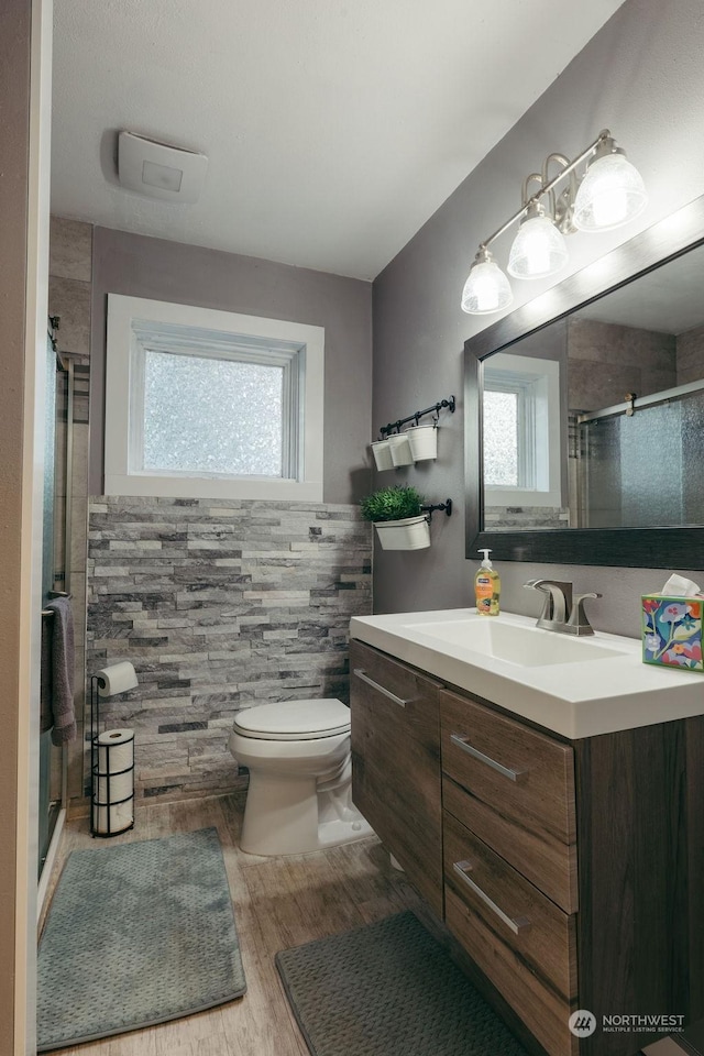 bathroom featuring an enclosed shower, toilet, vanity, tile walls, and hardwood / wood-style flooring