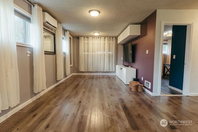 interior space featuring a textured ceiling, light hardwood / wood-style floors, and an AC wall unit