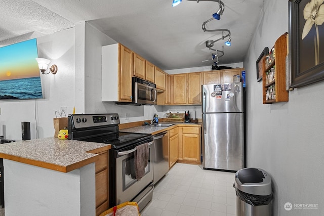 kitchen with sink, a textured ceiling, track lighting, kitchen peninsula, and stainless steel appliances