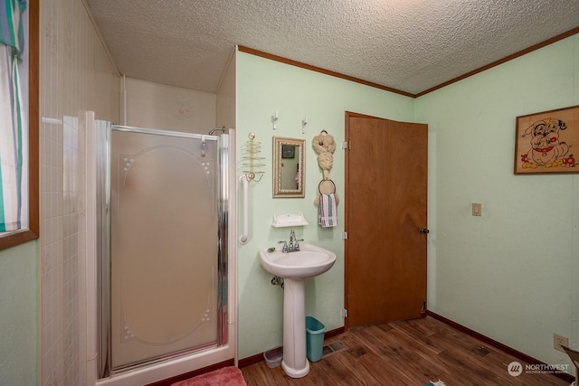 bathroom featuring a shower with door, wood-type flooring, a textured ceiling, and sink