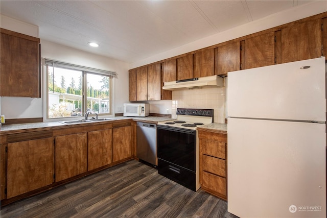 kitchen with dark hardwood / wood-style flooring, sink, decorative backsplash, and white appliances