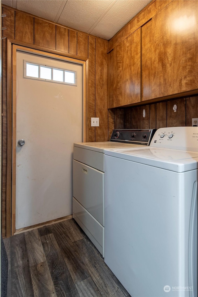 washroom with dark hardwood / wood-style floors, independent washer and dryer, wood walls, and cabinets