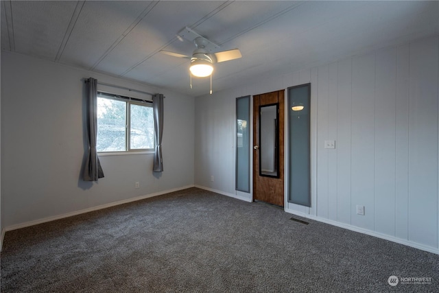 empty room with ceiling fan and dark carpet