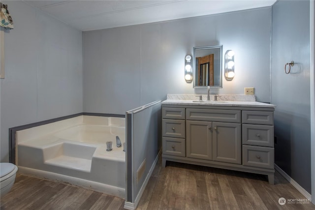 bathroom with hardwood / wood-style floors, a bathtub, vanity, and toilet