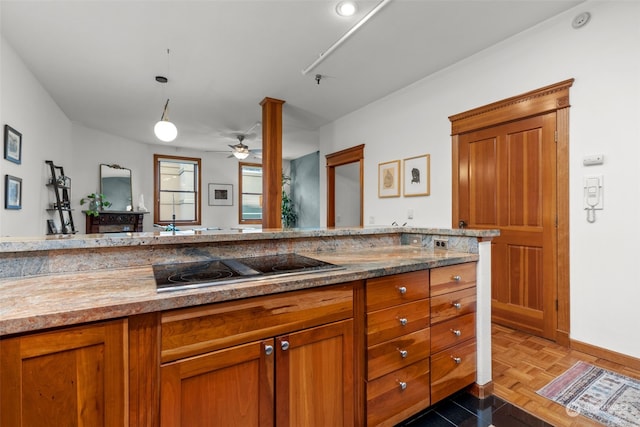 kitchen featuring light stone countertops, ceiling fan, hanging light fixtures, parquet flooring, and stovetop