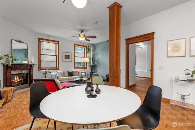 dining area featuring ornate columns, ceiling fan, and light parquet flooring