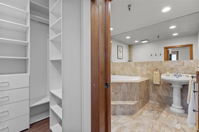 bathroom featuring tiled tub and sink