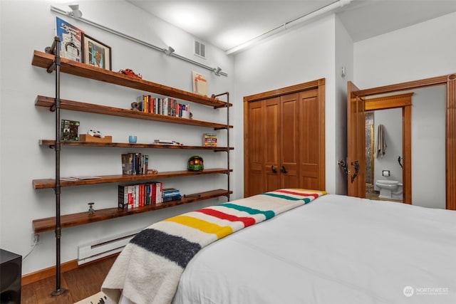 bedroom featuring baseboard heating, dark wood-type flooring, and a closet