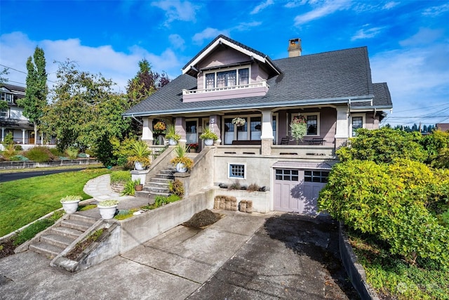 view of front of house featuring covered porch, a front yard, and a garage