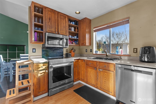 kitchen with stainless steel appliances, sink, and light hardwood / wood-style flooring