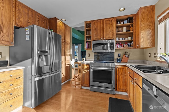 kitchen featuring stainless steel appliances, tasteful backsplash, sink, and light wood-type flooring