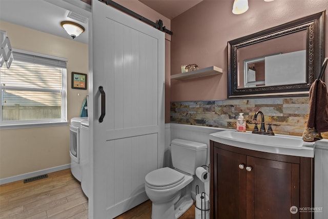 bathroom featuring washing machine and dryer, wood-type flooring, vanity, and toilet