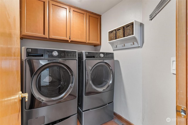 clothes washing area with separate washer and dryer and cabinets