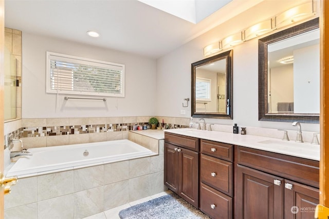 bathroom featuring tile patterned floors, tiled bath, and vanity