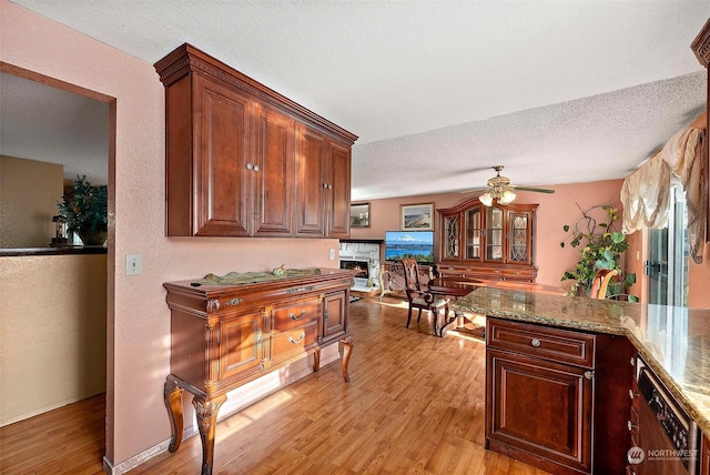 kitchen with a textured ceiling, ceiling fan, light hardwood / wood-style floors, and light stone counters