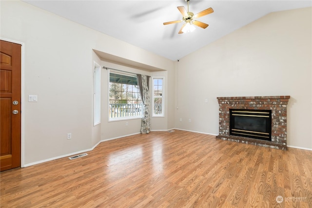 unfurnished living room featuring ceiling fan, light hardwood / wood-style floors, vaulted ceiling, and a brick fireplace