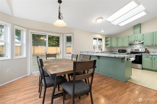 dining space with light wood-type flooring and vaulted ceiling with skylight