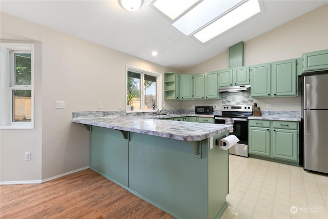 kitchen with stainless steel appliances, backsplash, kitchen peninsula, lofted ceiling with skylight, and a breakfast bar area