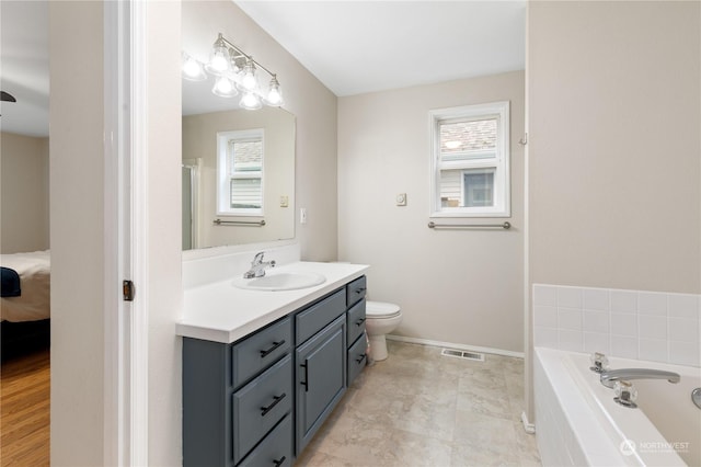 bathroom with vanity, a relaxing tiled tub, and toilet