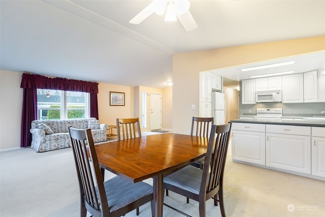 dining space with light carpet, vaulted ceiling, and ceiling fan