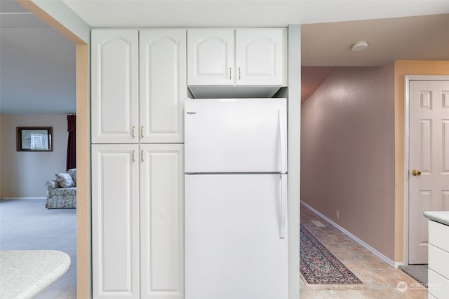 kitchen featuring light carpet, white refrigerator, and white cabinetry