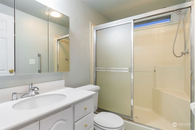 bathroom featuring vanity, toilet, and a shower with door