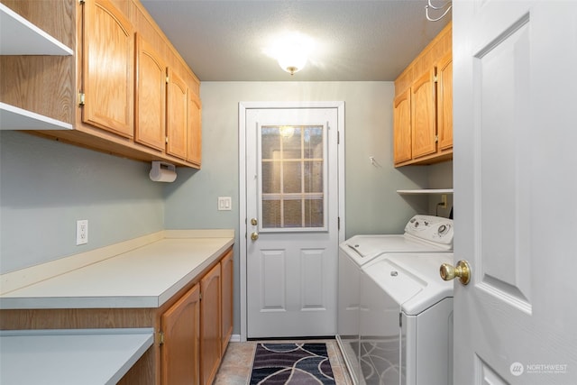 clothes washing area featuring washing machine and dryer, cabinets, and a textured ceiling