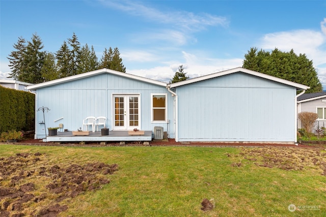 back of house featuring a lawn, a wooden deck, and french doors