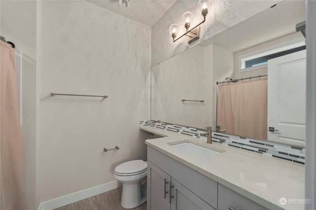 bathroom with tasteful backsplash, vanity, wood-type flooring, and toilet