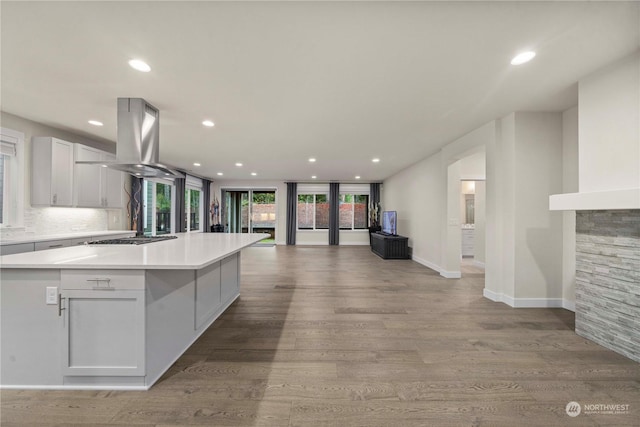 kitchen featuring island exhaust hood, light wood-type flooring, white cabinets, a kitchen island, and stainless steel gas stovetop