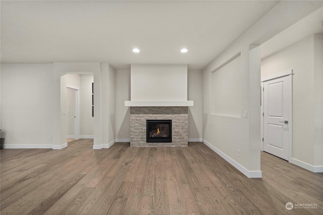 unfurnished living room featuring a stone fireplace and light hardwood / wood-style flooring