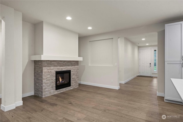 unfurnished living room with a stone fireplace and light hardwood / wood-style floors