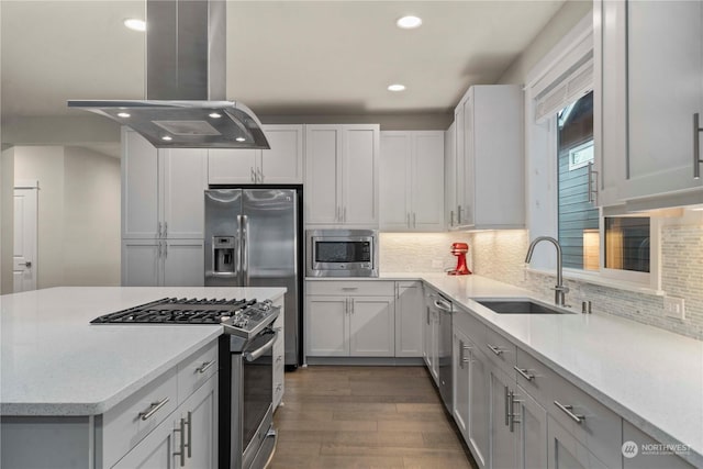 kitchen featuring island exhaust hood, decorative backsplash, stainless steel appliances, dark wood-type flooring, and sink