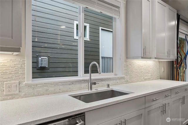 kitchen featuring backsplash, light stone countertops, sink, and white cabinets