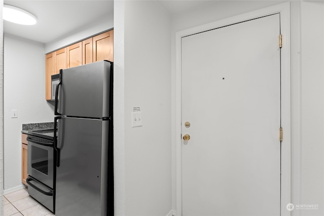 kitchen with black electric range oven, light tile patterned floors, light brown cabinets, and stainless steel refrigerator