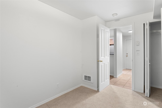 unfurnished bedroom with light carpet and a closet