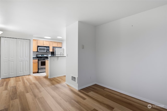 kitchen with light brown cabinets, electric range, white refrigerator, and light hardwood / wood-style flooring