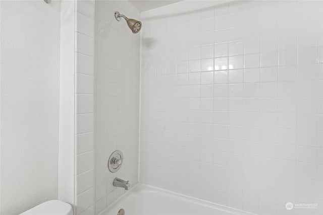 bathroom featuring tiled shower / bath combo and toilet