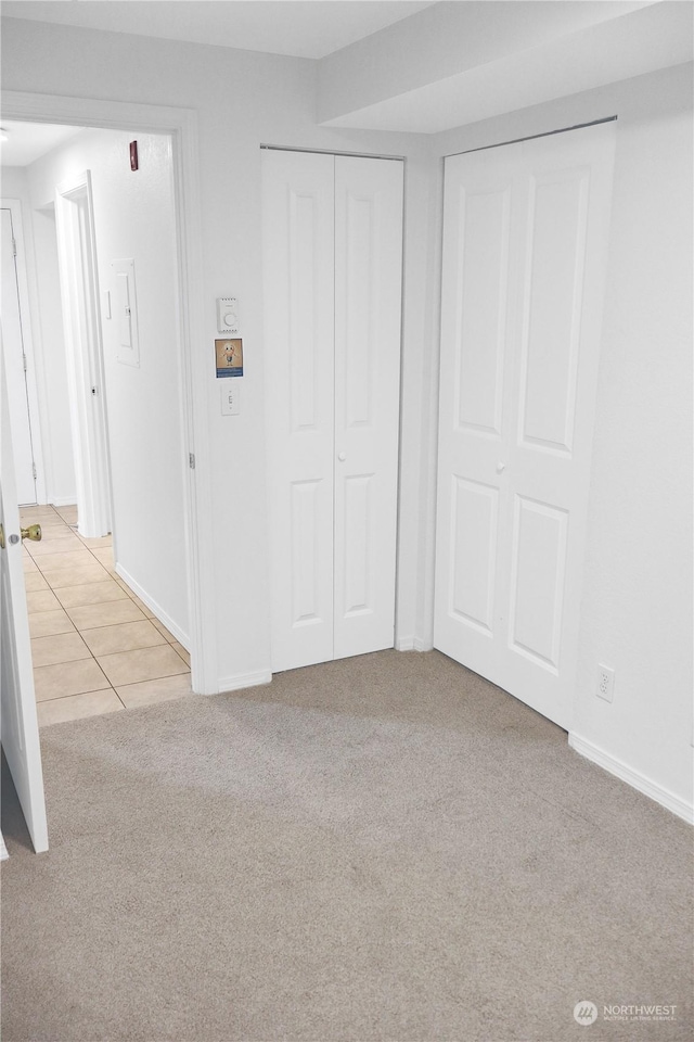 unfurnished bedroom featuring multiple closets and light colored carpet