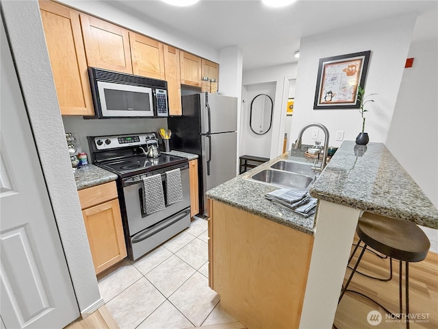 300 10th Ave Unit B-105, Seattle, WA 98122 - kitchen featuring appliances with stainless steel finishes, a sink, a peninsula, a kitchen bar, and light brown cabinets