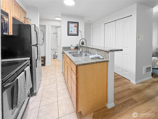 300 10th Ave Unit B-105, Seattle, WA 98122 - kitchen featuring a sink, stainless steel appliances, baseboards, light brown cabinets, and light stone counters