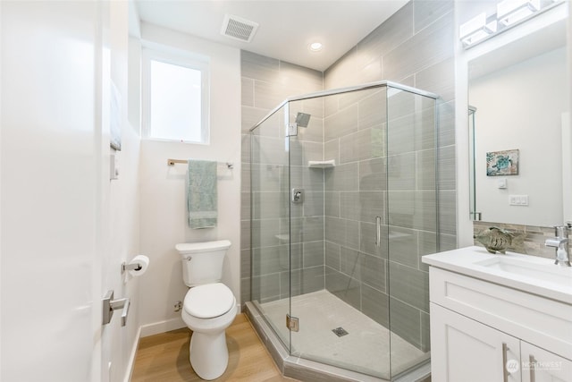 bathroom featuring vanity, hardwood / wood-style flooring, a shower with door, and toilet