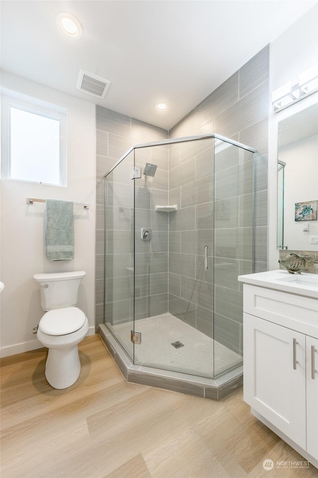 bathroom with vanity, toilet, a shower with door, and hardwood / wood-style floors