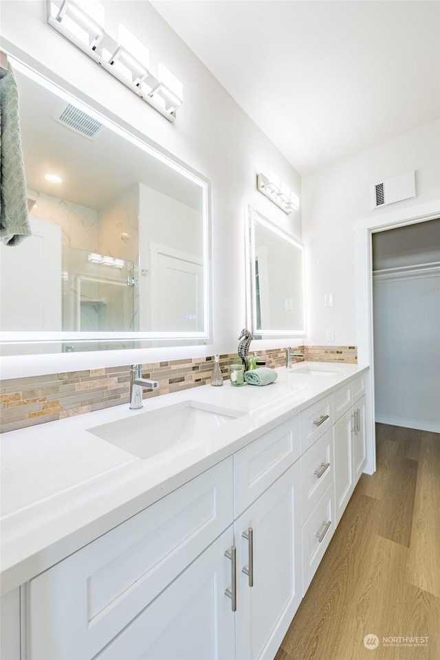 bathroom with tasteful backsplash, vanity, hardwood / wood-style floors, and walk in shower