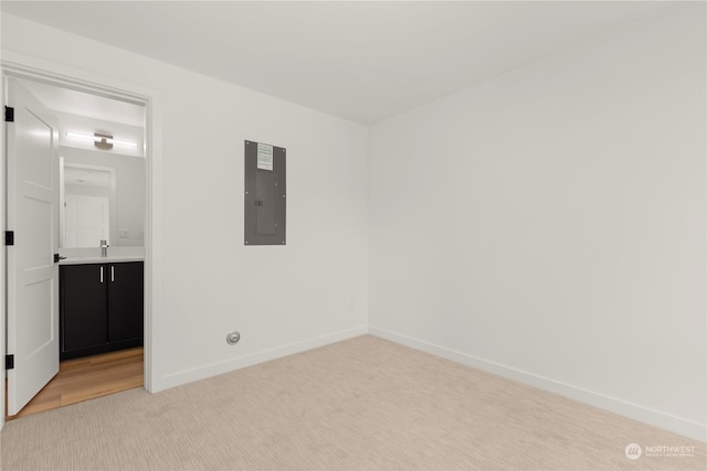 unfurnished bedroom featuring sink, light carpet, and electric panel