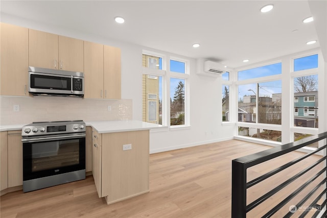 kitchen featuring a wall mounted air conditioner, light brown cabinets, appliances with stainless steel finishes, light hardwood / wood-style floors, and kitchen peninsula