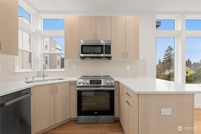 kitchen with kitchen peninsula, appliances with stainless steel finishes, light brown cabinets, and sink