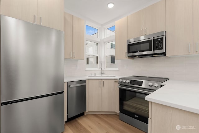 kitchen featuring light brown cabinets, stainless steel appliances, and sink