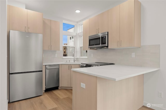 kitchen featuring kitchen peninsula, appliances with stainless steel finishes, and light brown cabinetry