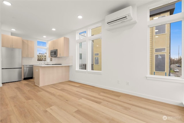 kitchen with a wall mounted air conditioner, appliances with stainless steel finishes, light brown cabinets, and tasteful backsplash